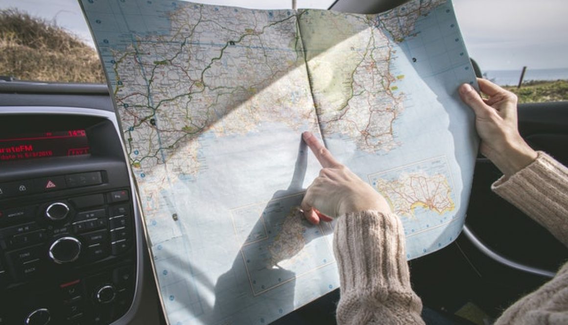 woman pointing at a map and finding the best american road trip routes