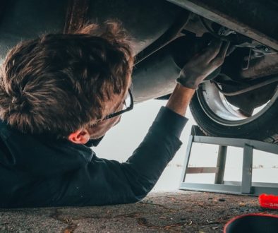 A man under a car checking for front end alignment symptoms