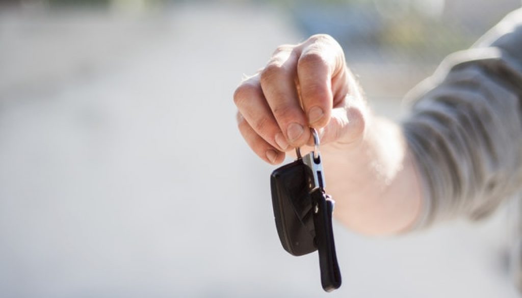 man handing over car keys with questions to ask when buying a used car